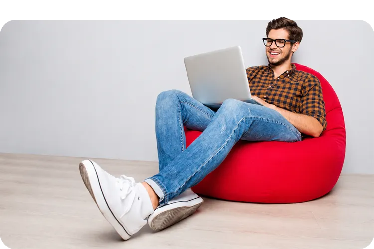 Hombre joven sonriendo mientras revisa su buzón de correspondencia en el portátil